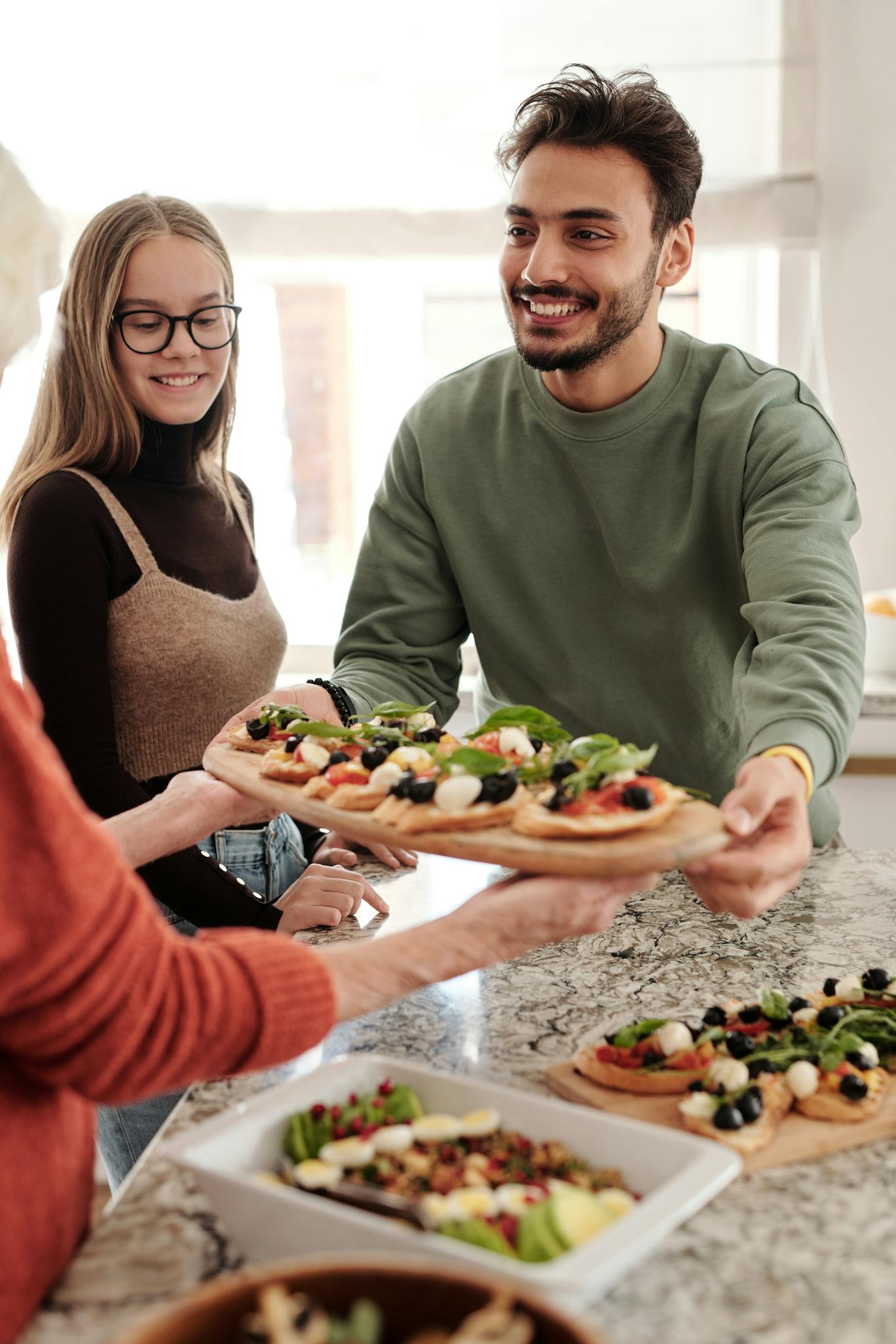 A cheerful family enjoys sharing freshly made vegetable flatbread in a cozy kitchen setting.
