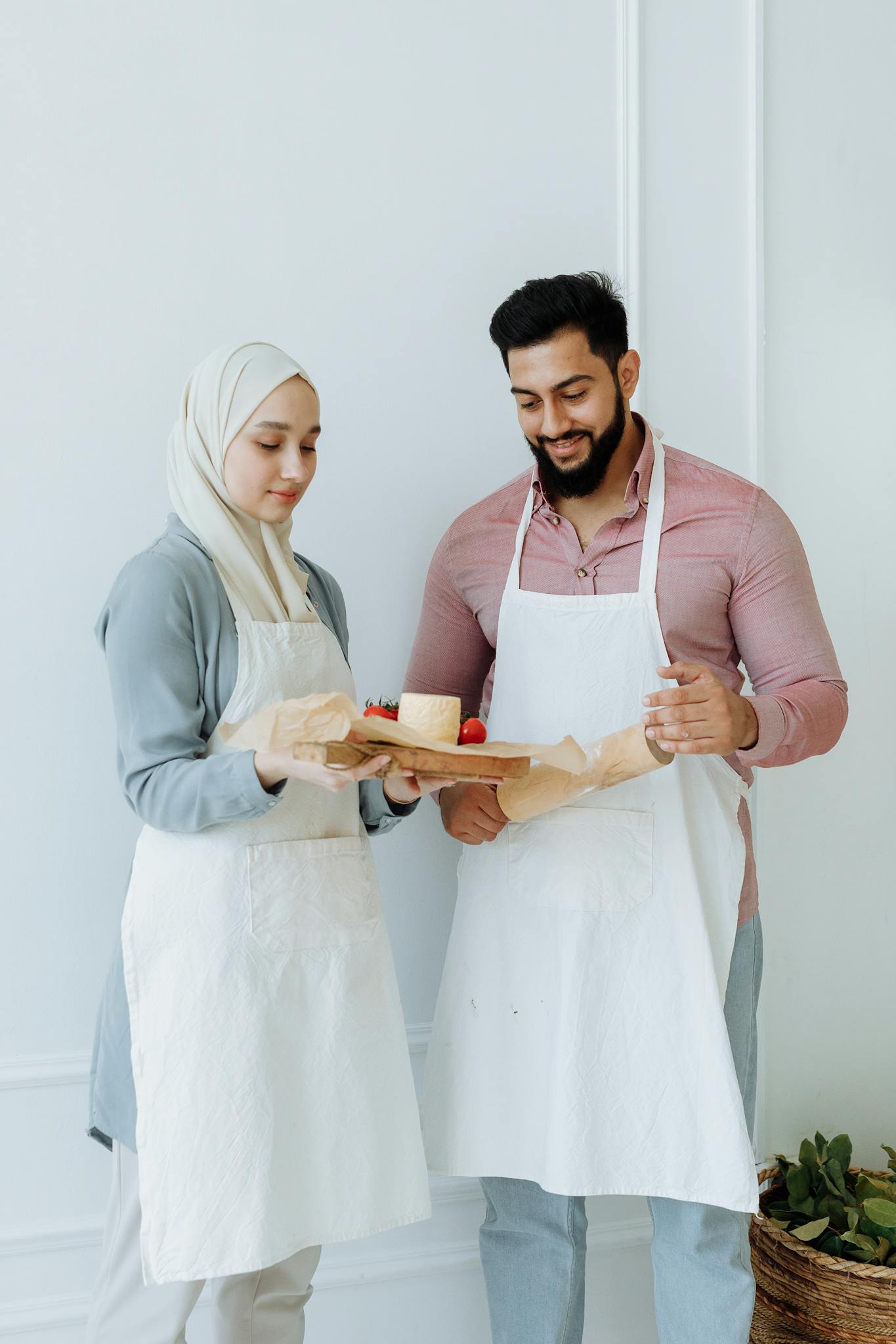 A couple happily prepares food together, showcasing love and teamwork.