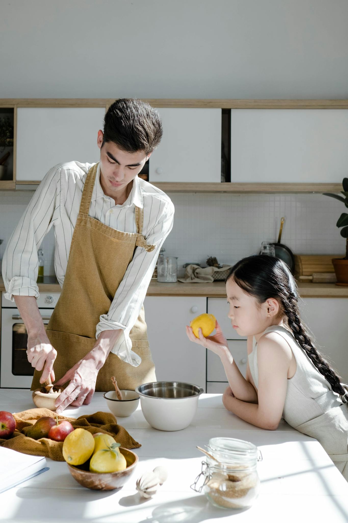 Father and daughter preparing food in a sunlit kitchen, enjoying quality time.