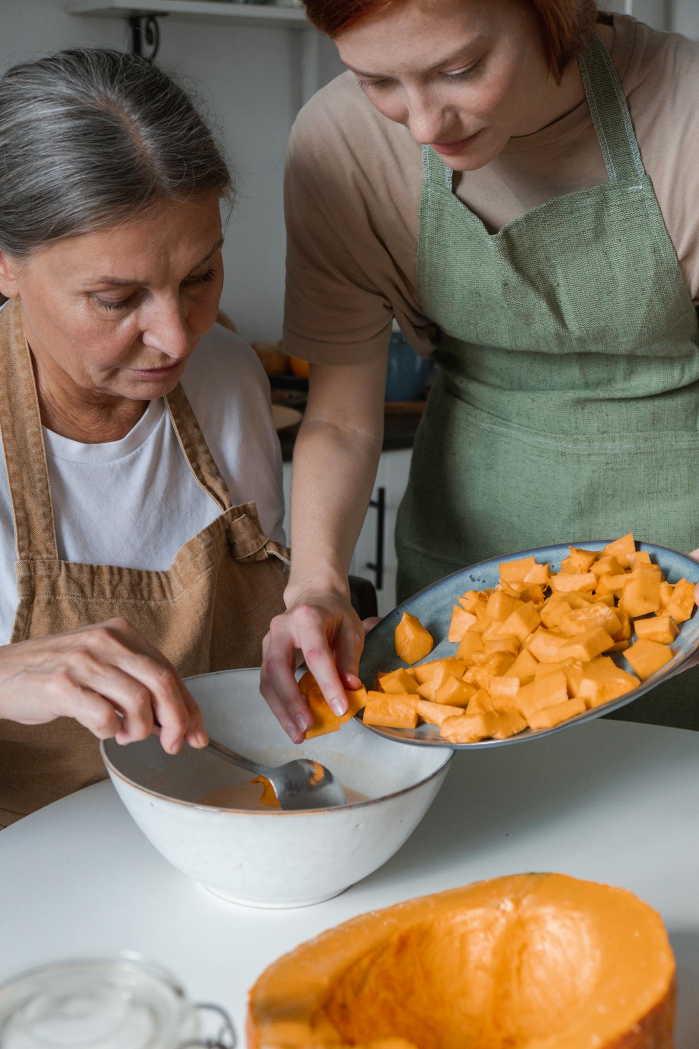 Mother and daughter cooking together, preparing squash for a meal in a cozy kitchen.